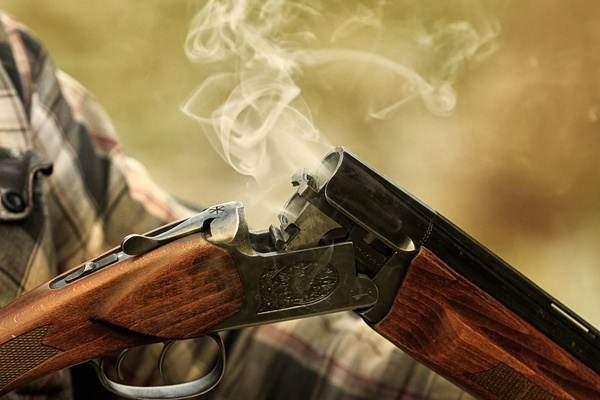 Smoke curling from an open shotgun
