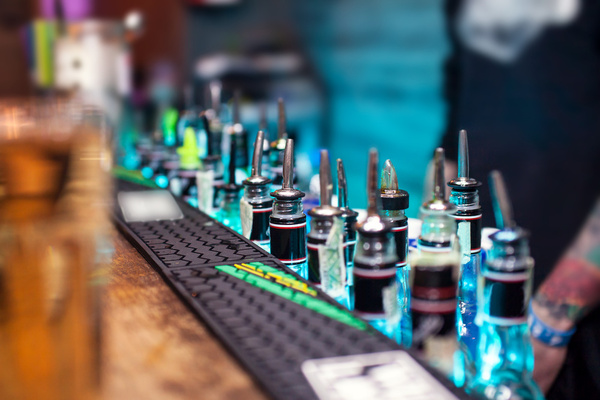 Bottles with pourers lined up along a bar