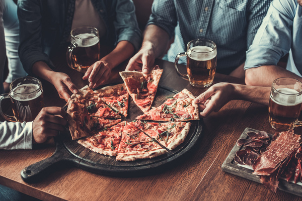 A crew sharing pizza and beers around a table