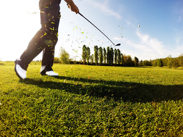 A golfer swinging through on the fairway